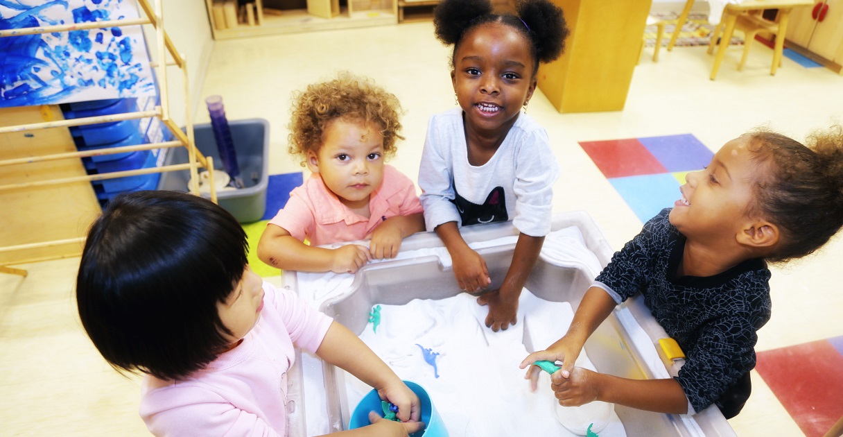 Preschool children and their teacher build with blocks in their classroom.