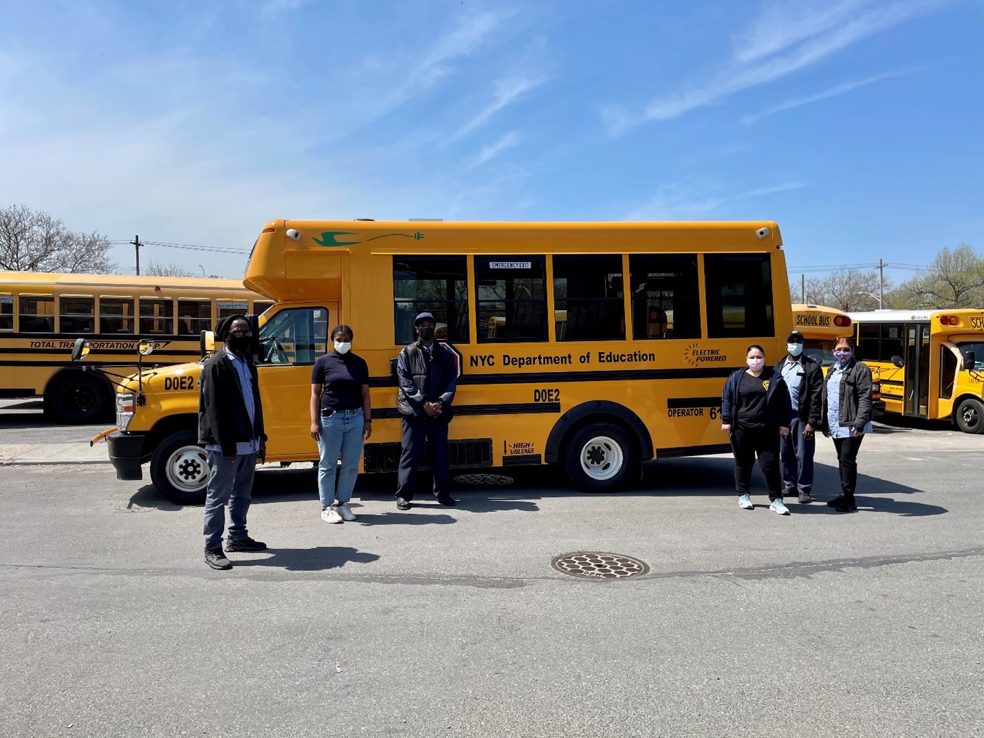 A Via school bus in a lot with drivers standing outside