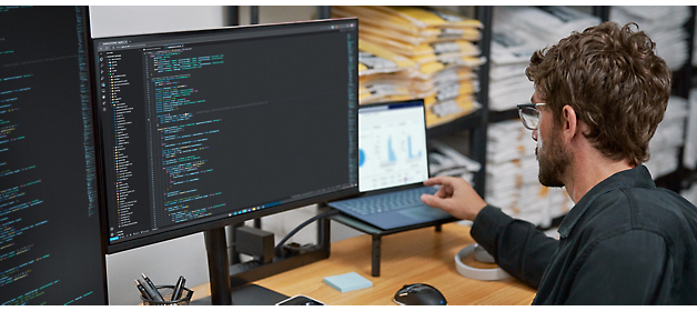 Software developer working on code at a dual-monitor workstation.