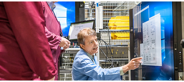 Two people in a control room analyzing data on computer screens.