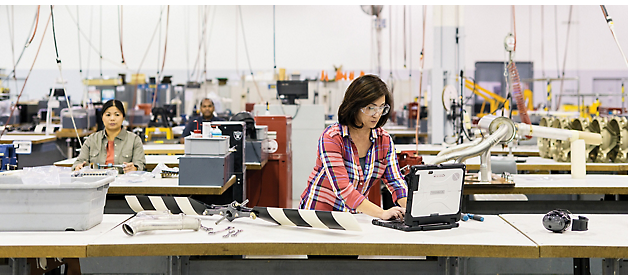 Two individuals working with aerospace components in an industrial manufacturing facility.