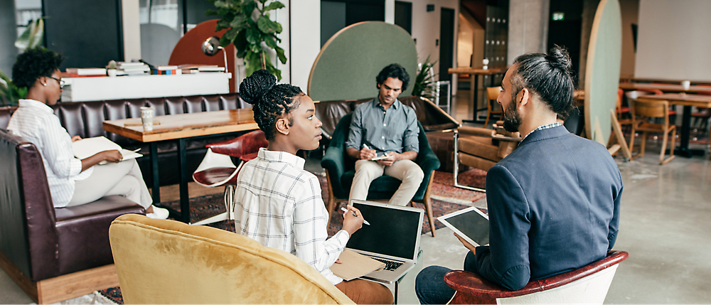 Two people are discussing, and another two people are doing some work.