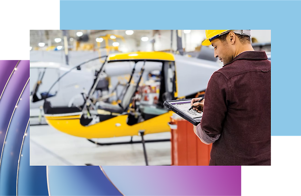 Trabalhador a inspecionar o progresso do fabrico de aeronaves com um tablet digital num hangar.