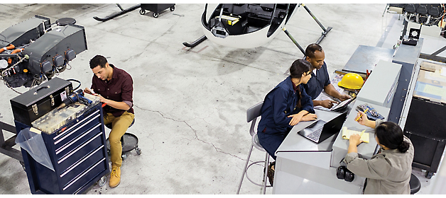 Team of engineers and technicians working on various tasks in an aircraft hangar.