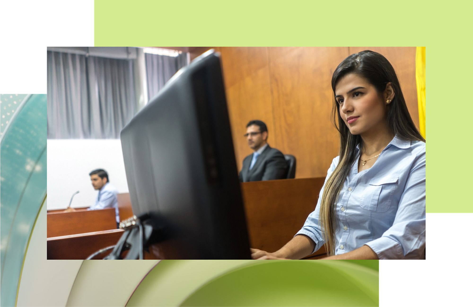 A young woman in a blue shirt at a desk with a computer in a courtroom; two men in the background