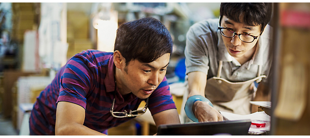 Two craftsmen in a workshop examining a piece closely.