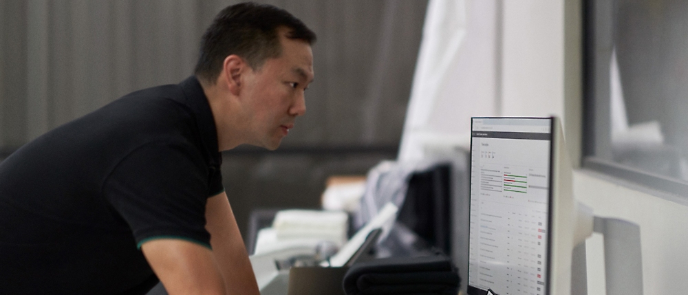 Man concentrating intently on a computer screen in a modern office setting.