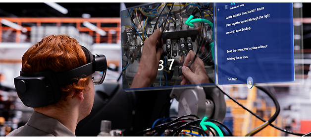 A technician wearing a virtual reality headset works on an electrical panel while referencing a digital overlay guide.