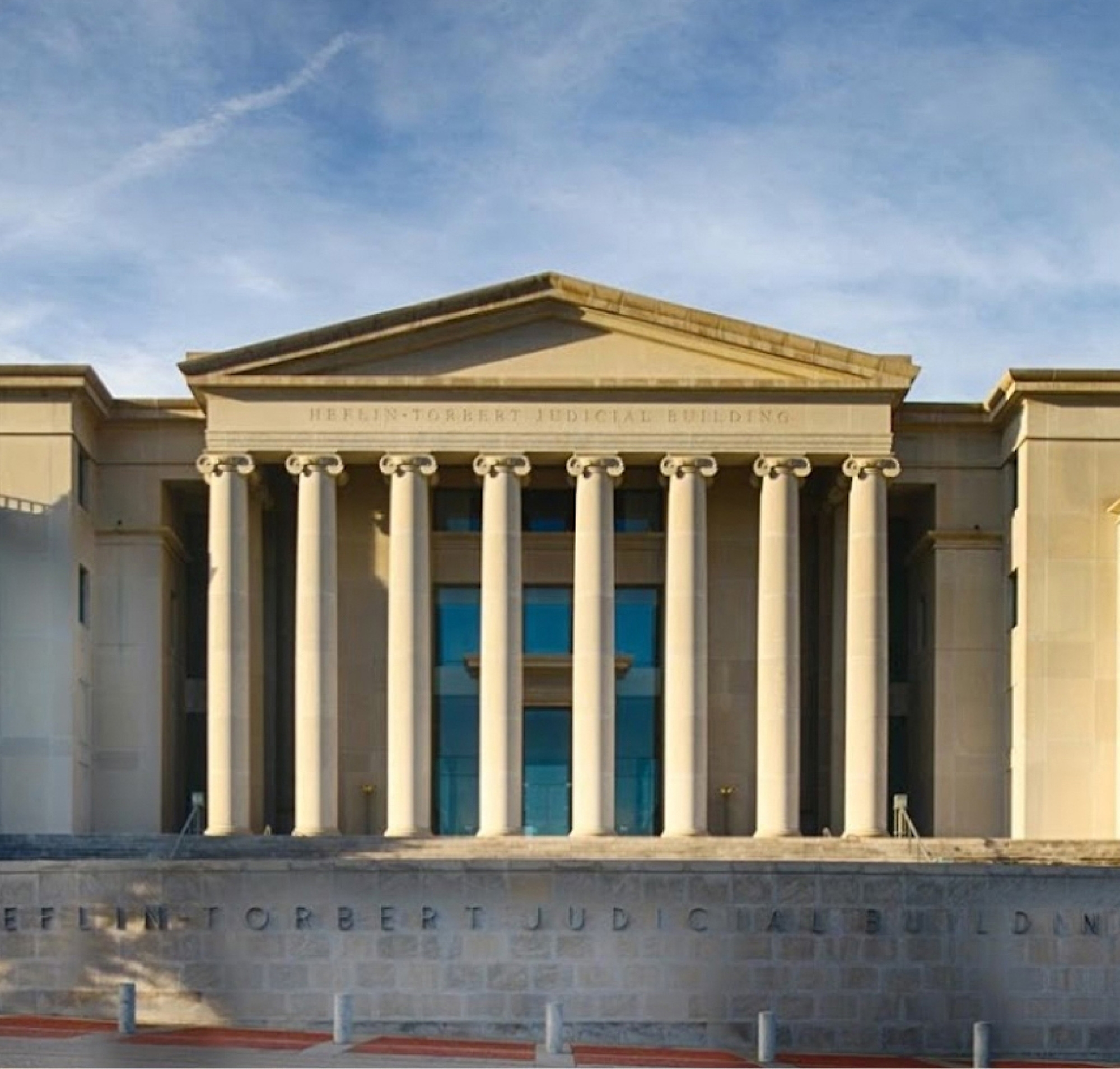 Front view of the heflin-torbert judicial building featuring a classical facade with columns under a clear sky.