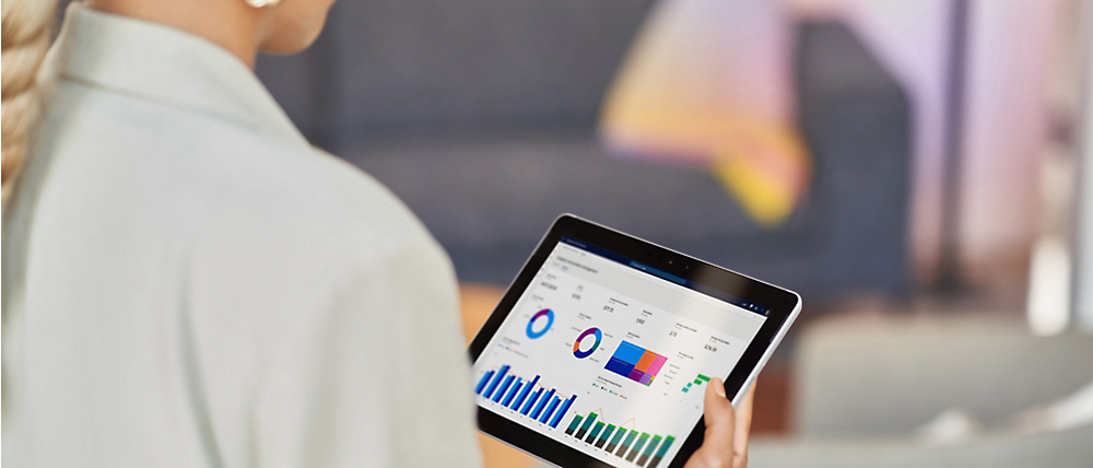 Person holding a tablet displaying colorful graphs and charts, indicating data analysis or business metrics.