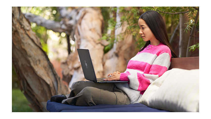 Young female adult outside working on a laptop.