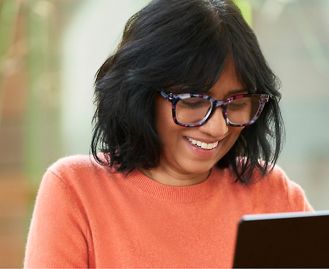 A woman wearing spectacles working on laptop