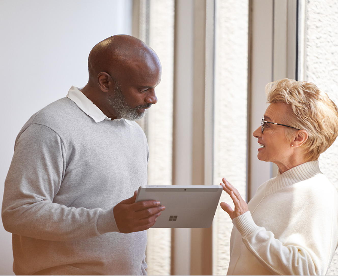 Ein Mann, der ein Surface Pro hält und mit einer Frau spricht