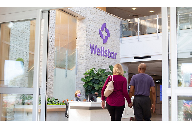 Dva lidé kráčí před budovou Wellstar