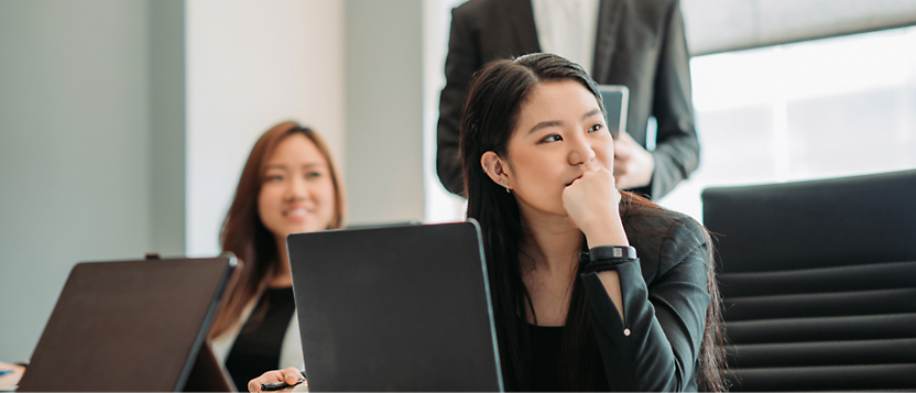 노트북을 펴고 다른 참석자와 함께 회의에 집중하여 경청하고 있는 비즈니스 복장을 한 젊은 동양인 여성 
