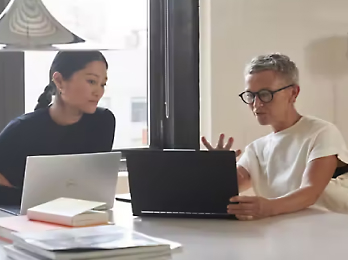 Two person's sitting and watching laptop,discussing on some topic.