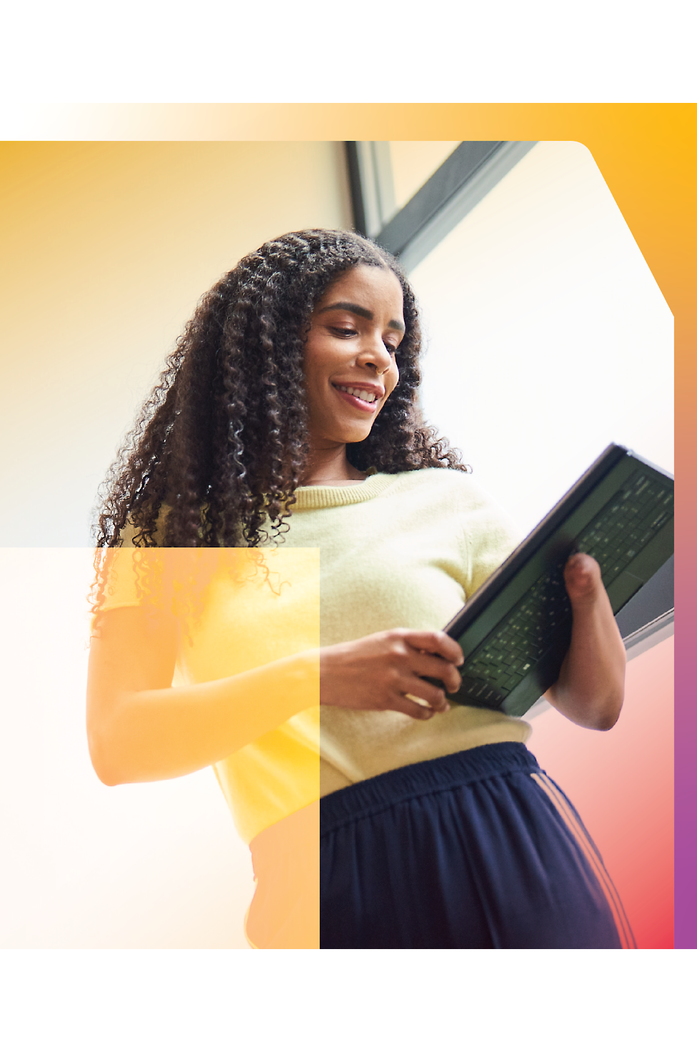 A woman with curly hair is holding a tablet.