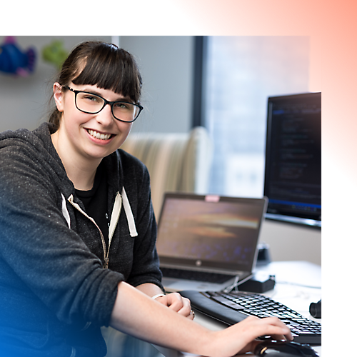 A woman working on her laptop with monitor