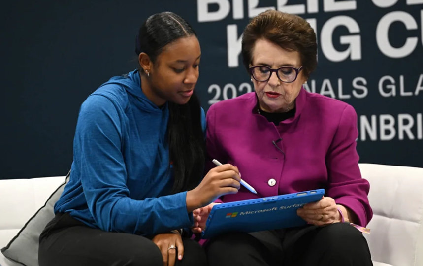 Billie Jean King and a young Black tennis player study performance data on a Surface.