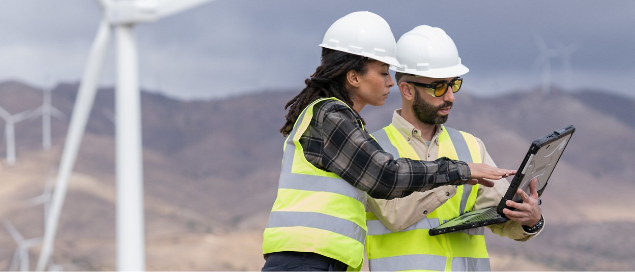 Dos personas con cascos blancos y chalecos de seguridad y mirando el portátil