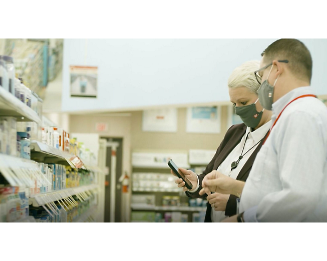 Two people wearing masks in a pharmacy.