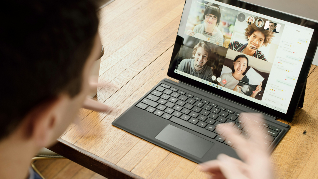 A man using a Surface laptop to meet virtually with friends