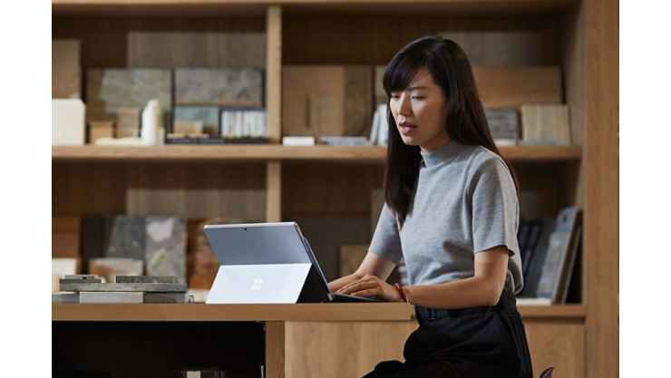 A person works on their Surface device in an office space