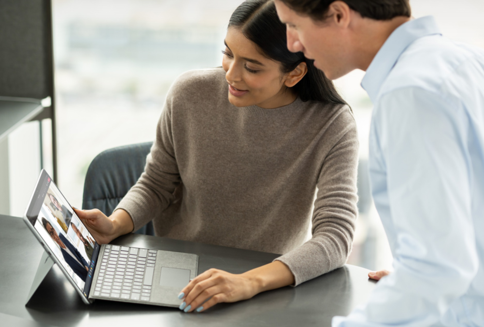 Co-workers sharing a Surface device for a virtual meeting