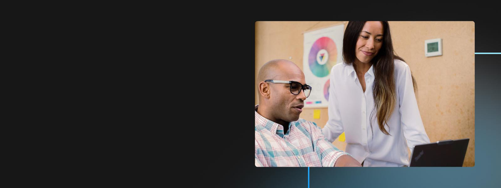 Two coworkers look at the screen of a Windows device