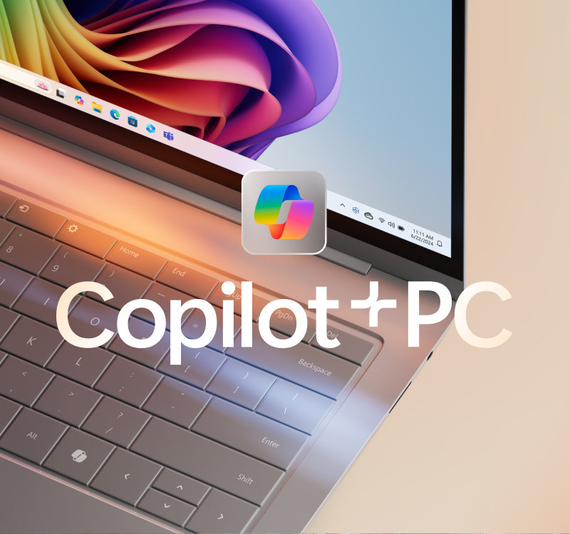 Copilot のロゴと色鮮やかなブルームが表示されたノート PC