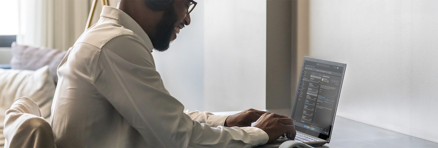 Un hombre sonriente sentado en una mesa escribe en su dispositivo Surface