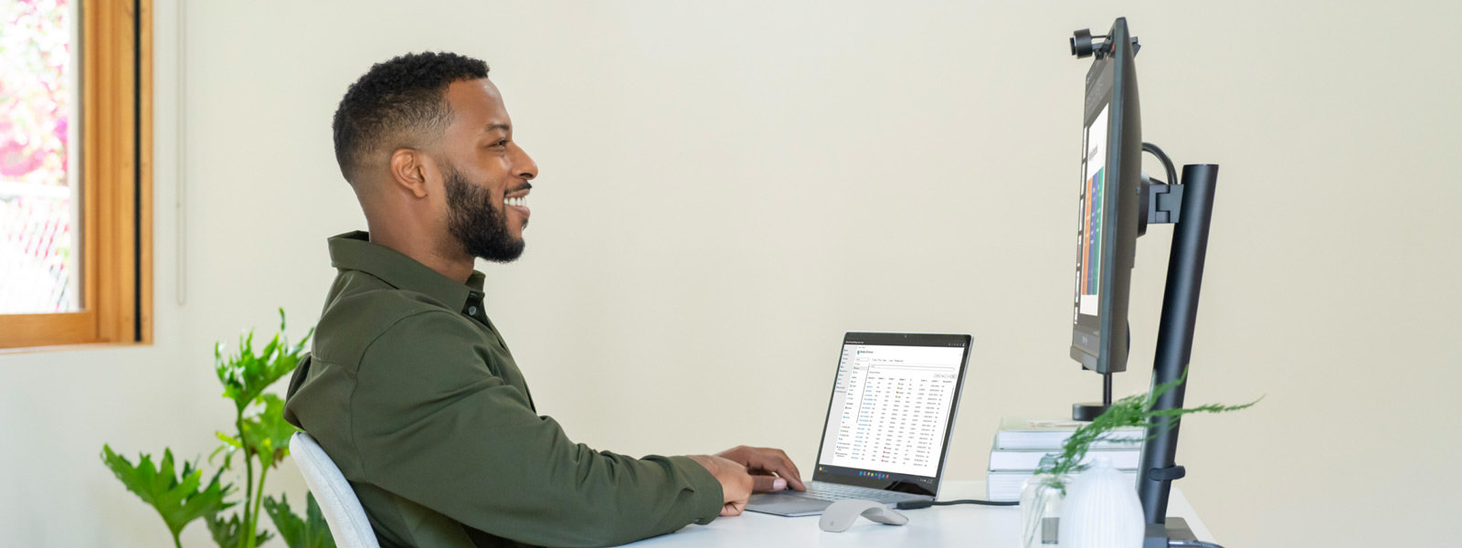 Man sitting at desk using a Surface device connected to a separate monitor