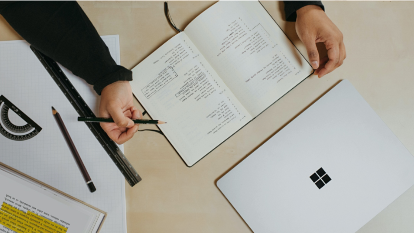 Person using a notebook next to a Surface laptop