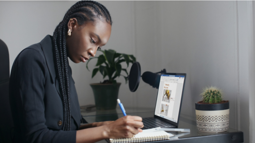 Student taking notes while using a Surface laptop