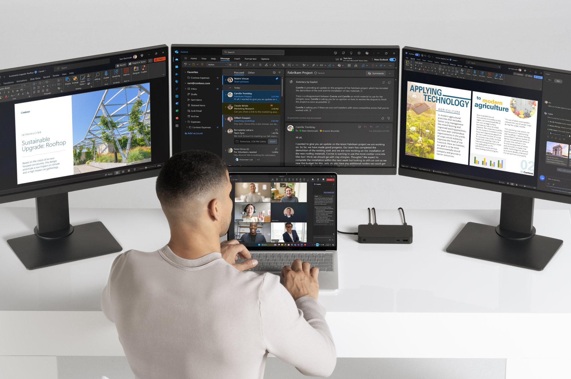 A man works on a Surface Laptop device, that is connected to three monitors through a Surface ThunderboltTM 4 Dock.