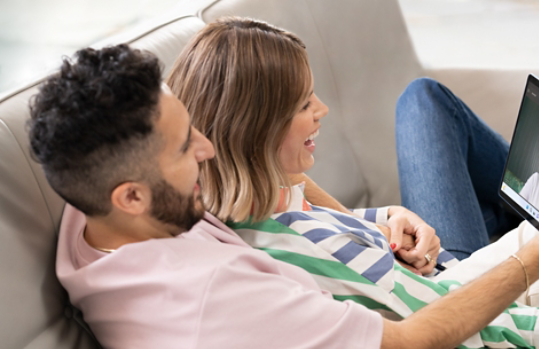 Two people lying together on a couch, video calling on their Surface device