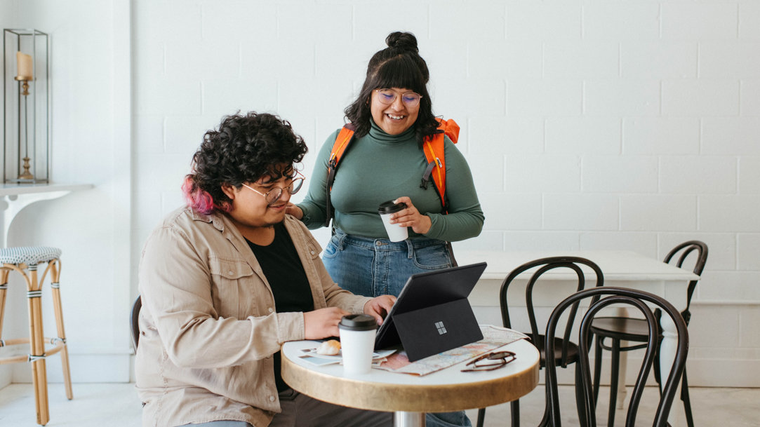 Two women laughing as one types on a Surface Pro 9 keyboard