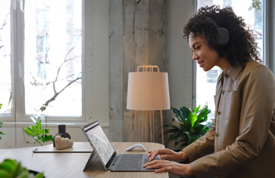 Woman wearing headphones and working on her Surface device