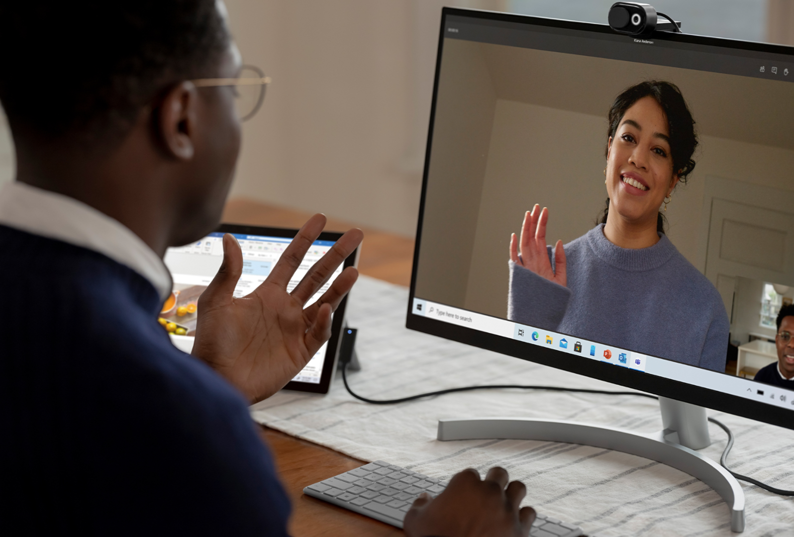 A man uses his Surface device connected to an external monitor and Microsoft Modern Webcam to talk with a colleague in Microsoft Teams call