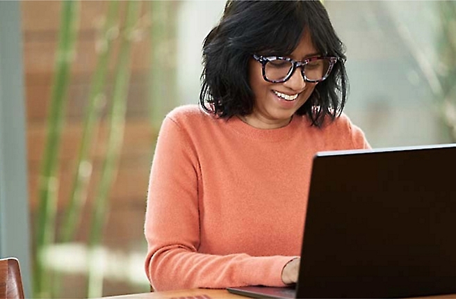 A woman wearing glasses is using a laptop.