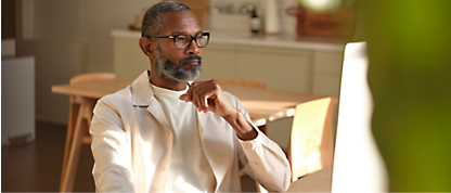 A black man sitting at a table looking at his phone.