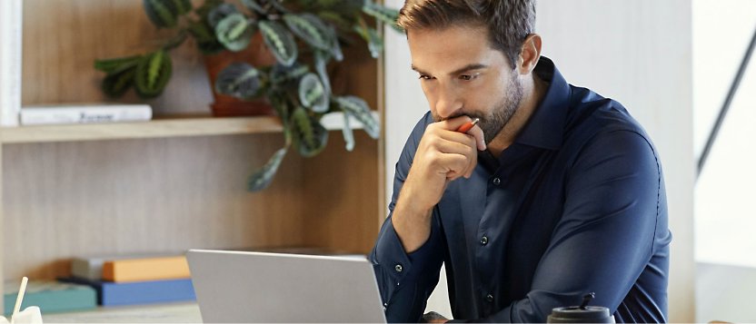 Eine Person, die ihren Laptop verwendet und eine Hand auf dem Kinn hat