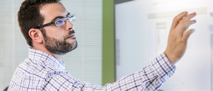 Eine Person, die eine Brille trägt und einen Touchscreen-Monitor verwendet