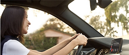 A woman driving a car with her hands on the steering wheel.