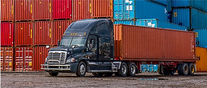 A semi truck is parked in front of containers.