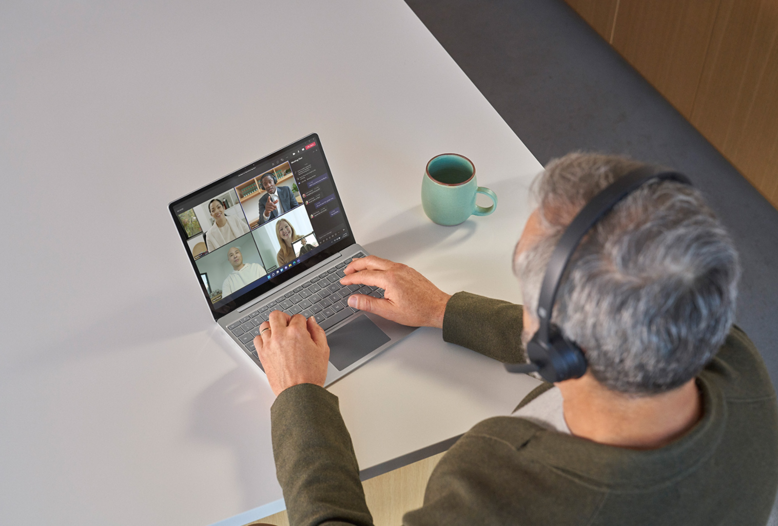 有人戴著 Surface Headphones 2 在 Surface Laptop Go 3 上進行 Teams 會議的俯視圖