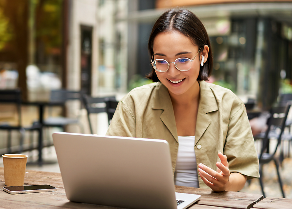 A woman is wearing glasses and sitting in front of computer screen