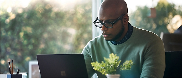 A person wearing spectacles working on his laptop