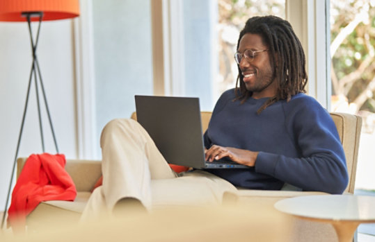 A man sitting on a couch working on his laptop