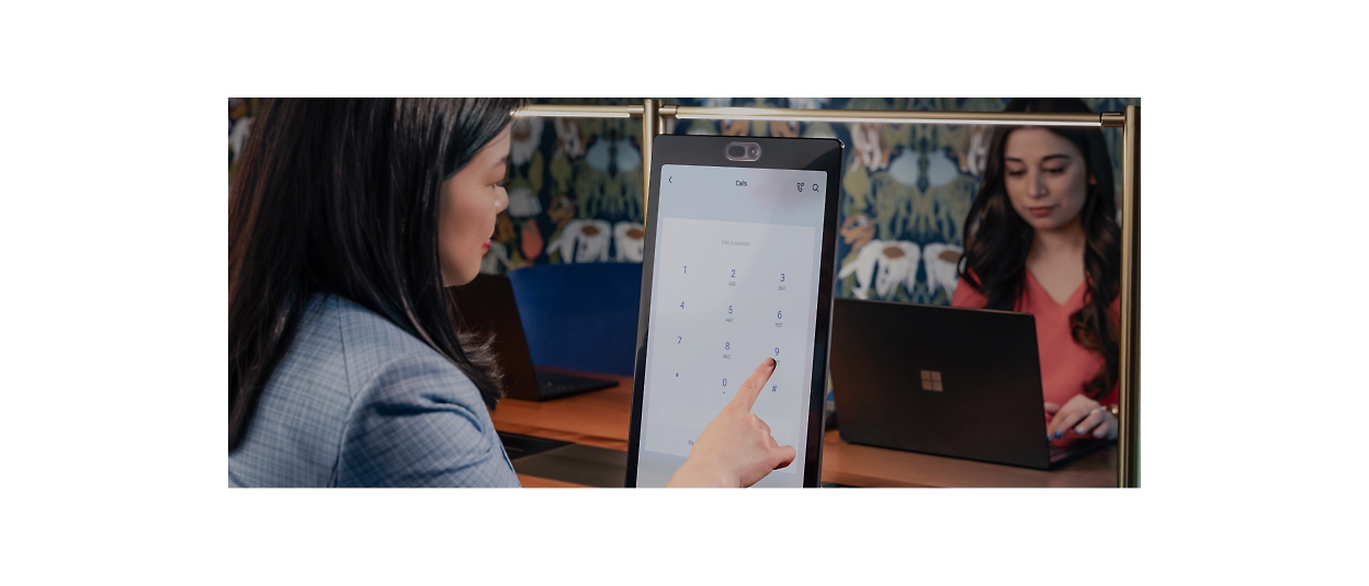 A woman is pointing to a screen in front of a laptop.